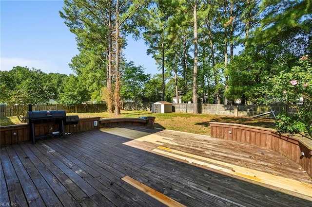 wooden deck with a fenced backyard, grilling area, a shed, and an outdoor structure
