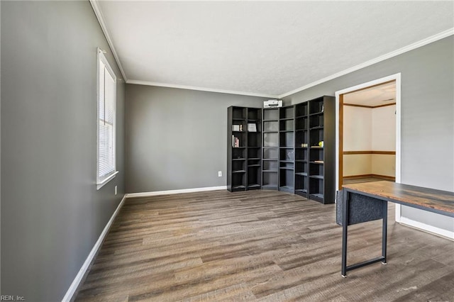 spare room with baseboards, crown molding, and wood finished floors