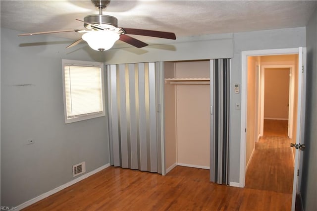 unfurnished bedroom featuring a textured ceiling, hardwood / wood-style floors, ceiling fan, and a closet