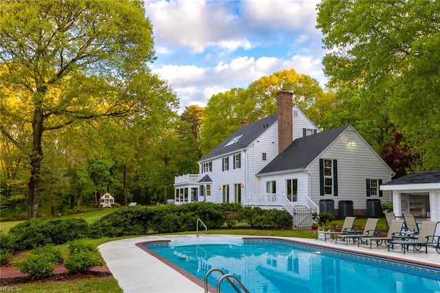 back of property with a swimming pool side deck and cooling unit