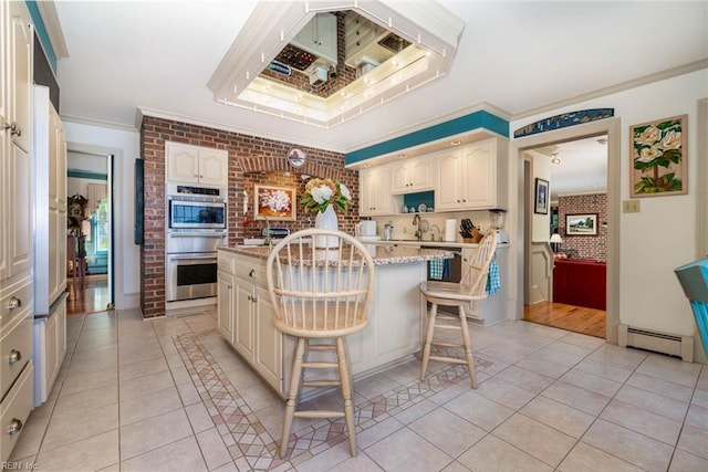 kitchen featuring stainless steel double oven, light stone counters, a breakfast bar area, a center island, and brick wall