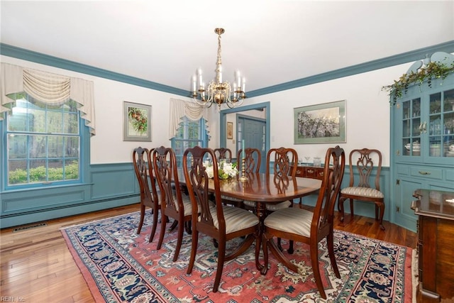 dining room with ornamental molding, a baseboard radiator, a notable chandelier, and hardwood / wood-style flooring