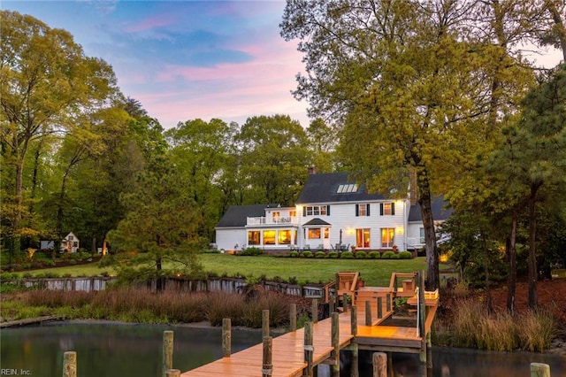 view of dock with a water view and a yard