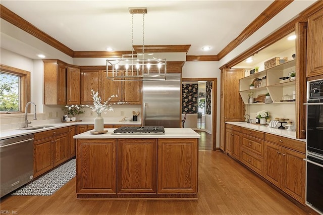 kitchen with a center island, stainless steel appliances, hanging light fixtures, and sink