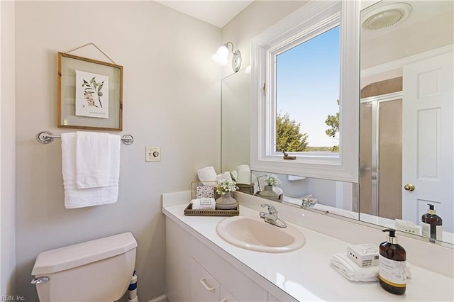 bathroom featuring toilet, vanity, and a shower with door