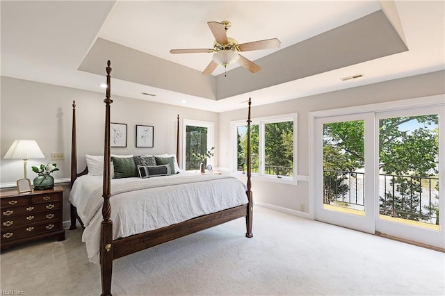 bedroom featuring access to exterior, light colored carpet, a tray ceiling, and ceiling fan