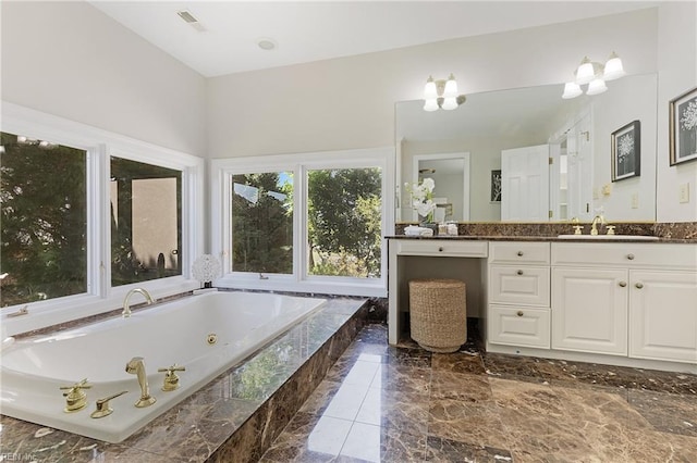 bathroom featuring vanity, an inviting chandelier, and tiled tub