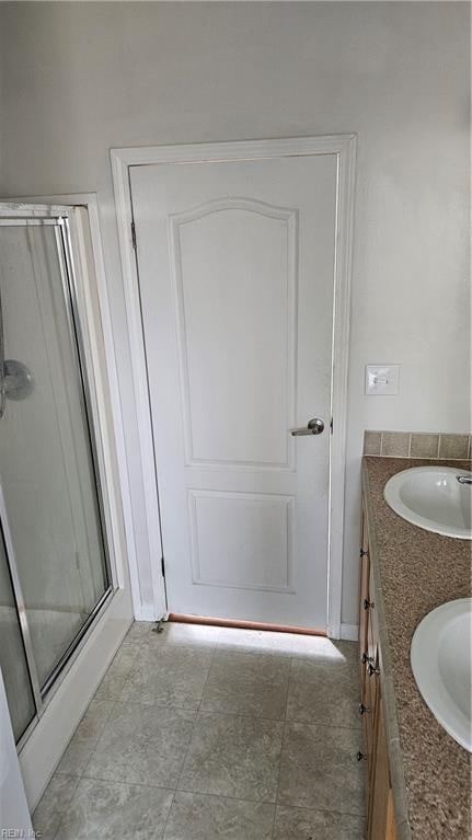 bathroom with tile patterned floors, a shower with door, and vanity