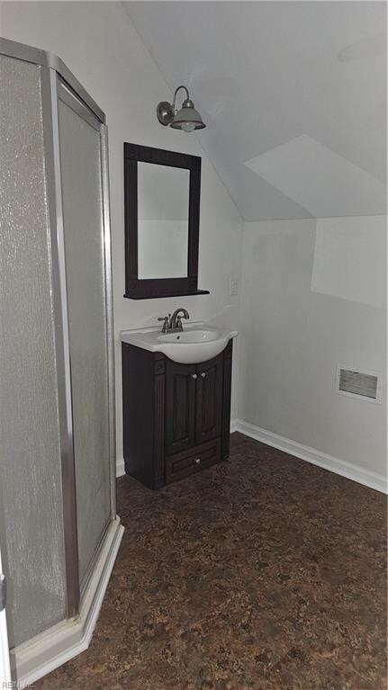 bathroom with vanity, walk in shower, and lofted ceiling