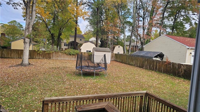 view of yard with a trampoline, a storage unit, and a wooden deck