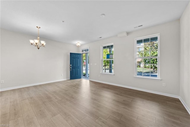 empty room with an inviting chandelier and hardwood / wood-style flooring