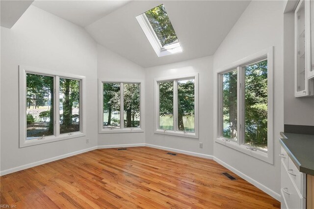 unfurnished sunroom with a wealth of natural light and vaulted ceiling with skylight