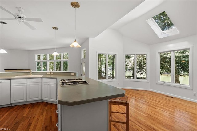 kitchen featuring dark wood-type flooring, hanging light fixtures, sink, ceiling fan, and white cabinets