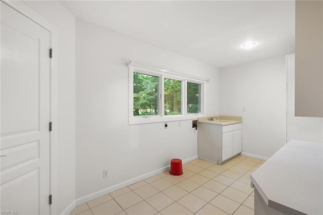 laundry area with electric dryer hookup, light tile patterned floors, cabinets, and sink