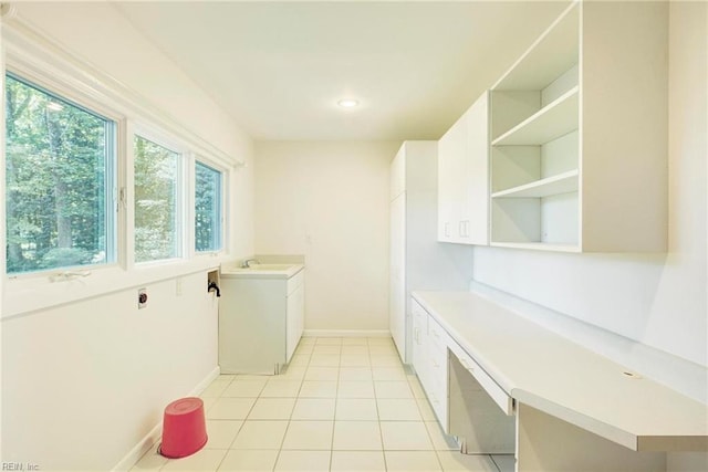 laundry area with electric dryer hookup, sink, cabinets, and light tile patterned flooring