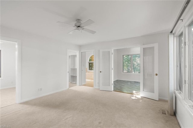 unfurnished bedroom featuring ceiling fan, light carpet, and ensuite bathroom