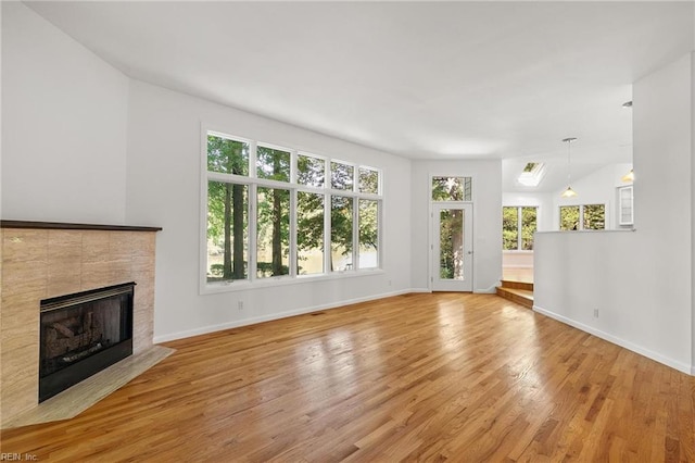 unfurnished living room with a tiled fireplace and light hardwood / wood-style floors