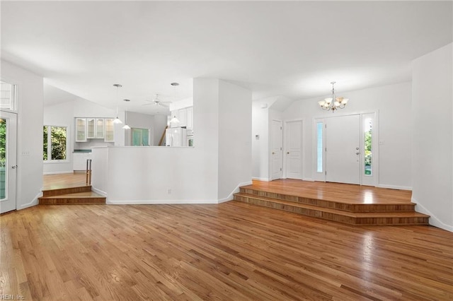 entrance foyer featuring light wood-type flooring, vaulted ceiling, and ceiling fan with notable chandelier