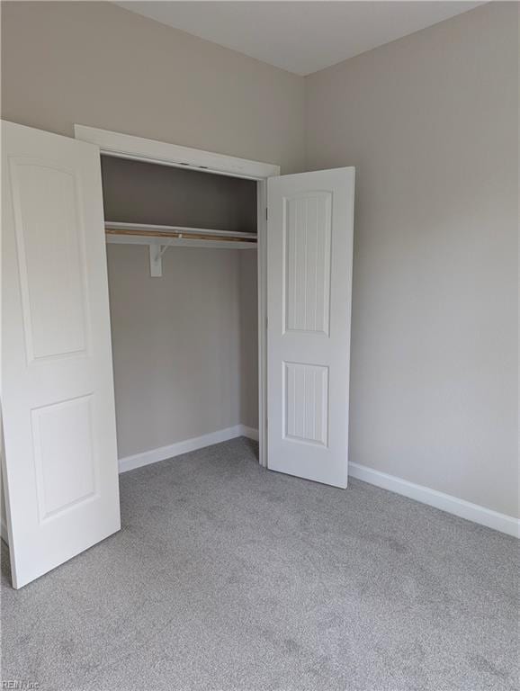 unfurnished bedroom featuring light carpet and a closet