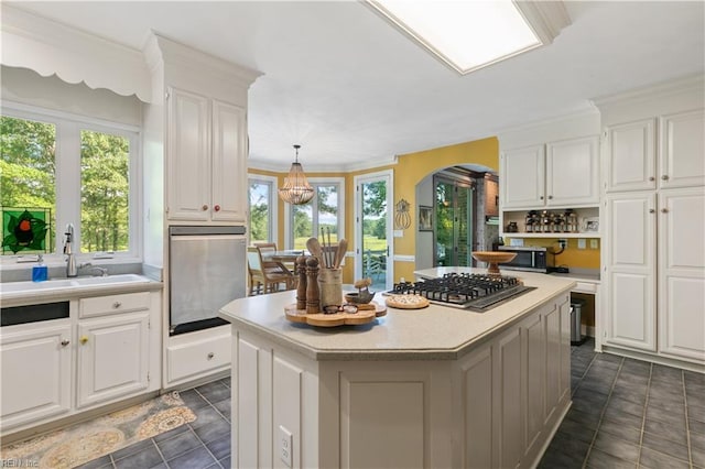 kitchen featuring a kitchen island, a sink, stainless steel appliances, light countertops, and white cabinetry