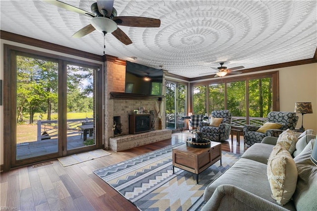 living room with crown molding, plenty of natural light, hardwood / wood-style floors, and a fireplace