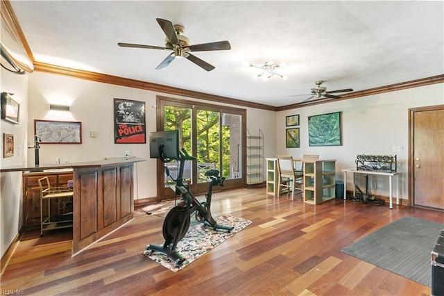 exercise room featuring ceiling fan, baseboards, ornamental molding, wet bar, and wood finished floors