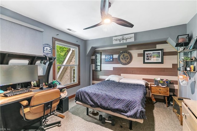 carpeted bedroom featuring ceiling fan and wooden walls