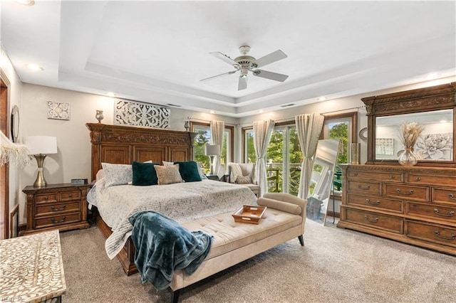 carpeted bedroom with a raised ceiling, a ceiling fan, and access to outside