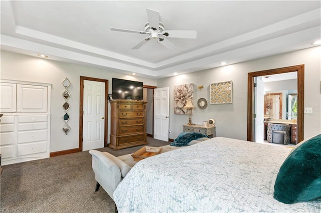 bedroom with ensuite bathroom, ceiling fan, carpet floors, and a tray ceiling