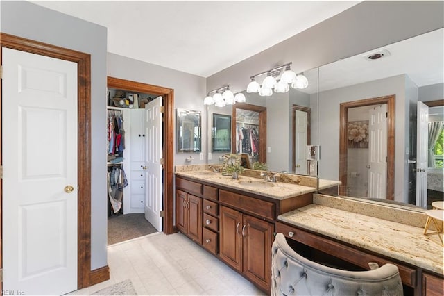 full bathroom with a walk in closet, double vanity, and a sink