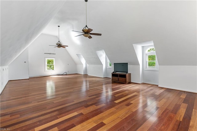 additional living space with vaulted ceiling, a healthy amount of sunlight, baseboards, and wood finished floors