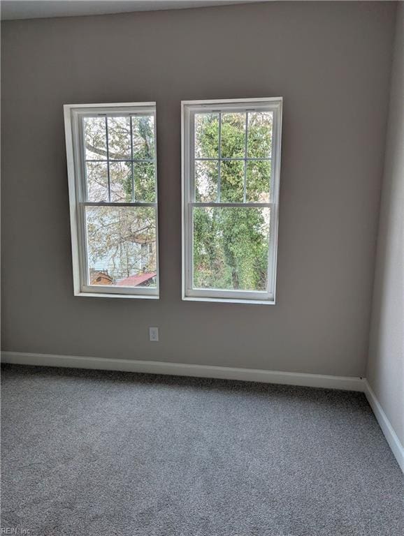 carpeted spare room featuring baseboards