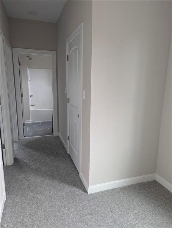 hallway featuring baseboards and carpet floors