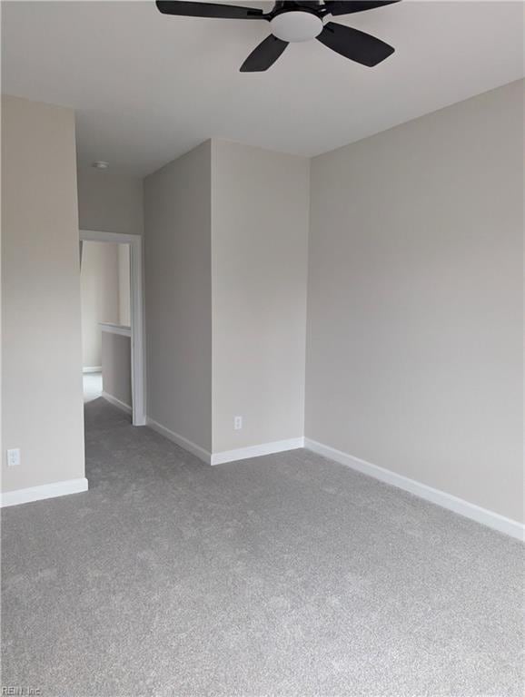 carpeted spare room featuring ceiling fan and baseboards