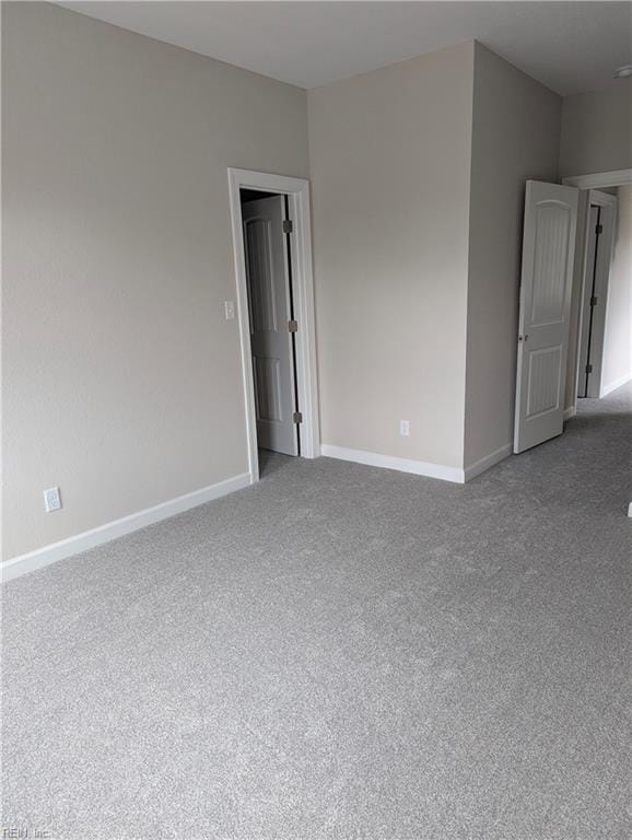 spare room with baseboards and light carpet