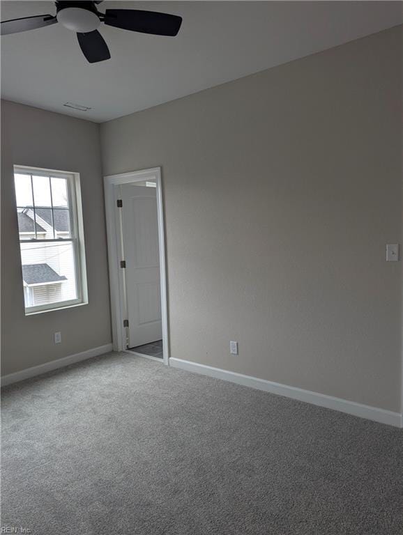 carpeted empty room featuring visible vents, baseboards, and a ceiling fan