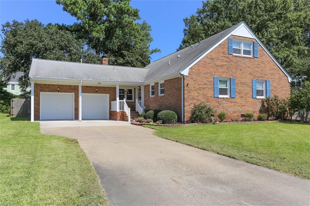 view of front of property with covered porch, a garage, and a front lawn