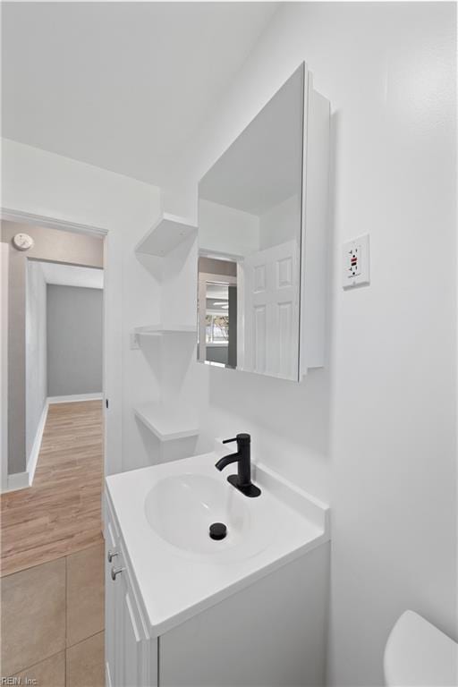 bathroom with toilet, hardwood / wood-style flooring, and vanity