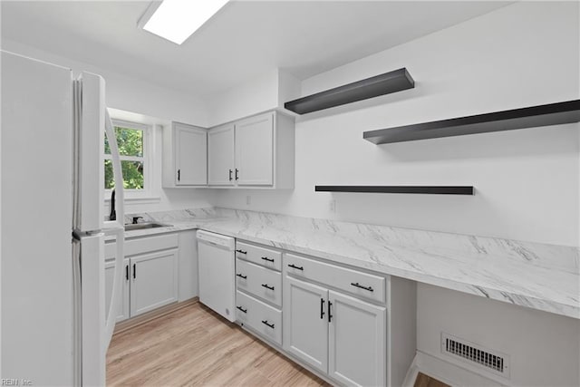 kitchen featuring light wood-type flooring, white appliances, light stone counters, and sink