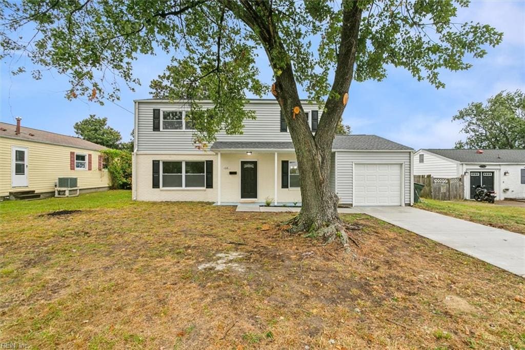 view of front of home featuring central AC, a garage, and a front yard