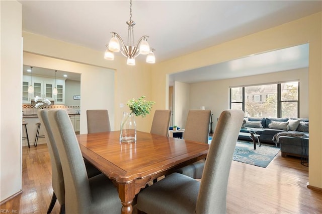 dining area with light hardwood / wood-style flooring and a notable chandelier