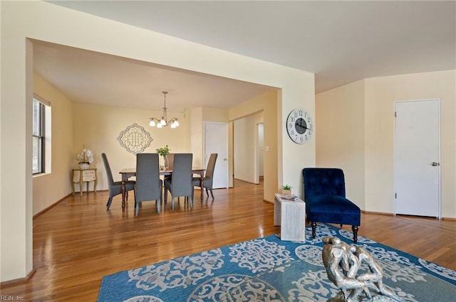 dining space with hardwood / wood-style floors and a notable chandelier