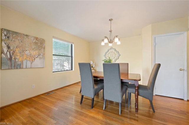 dining space featuring light wood-type flooring and an inviting chandelier