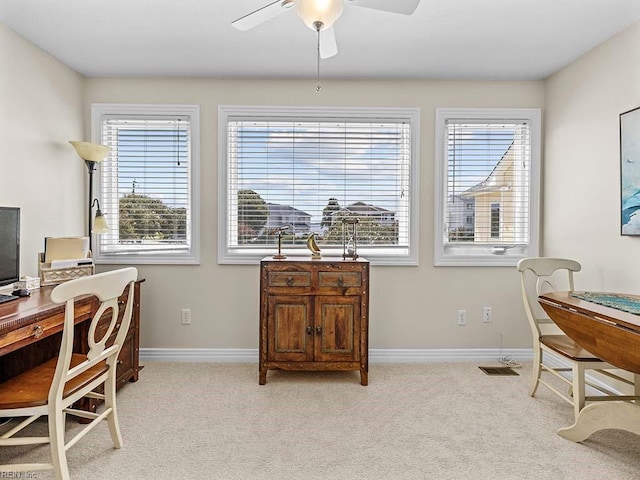 office area with a healthy amount of sunlight, ceiling fan, and light colored carpet