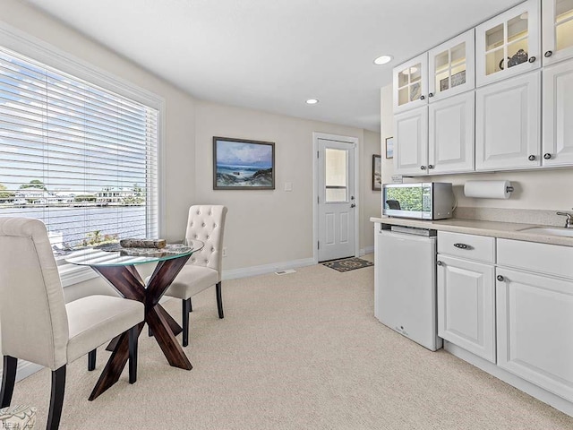 kitchen featuring light carpet, white dishwasher, and white cabinetry