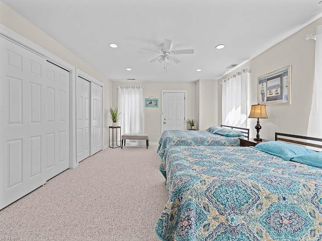 bedroom with multiple closets, multiple windows, ceiling fan, and carpet floors