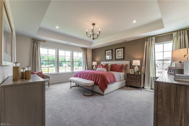 carpeted bedroom featuring multiple windows, a raised ceiling, and a chandelier