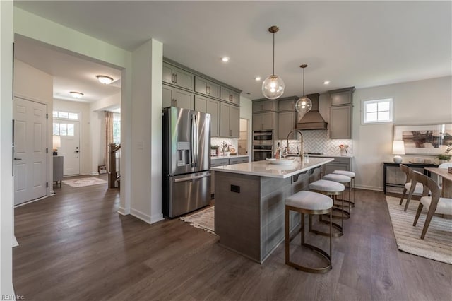 kitchen with a kitchen island with sink, appliances with stainless steel finishes, plenty of natural light, and decorative light fixtures