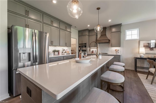 kitchen featuring dark hardwood / wood-style floors, custom exhaust hood, stainless steel appliances, and decorative light fixtures