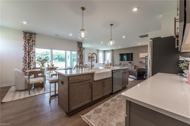 kitchen featuring dark hardwood / wood-style floors, sink, an island with sink, hanging light fixtures, and stainless steel appliances